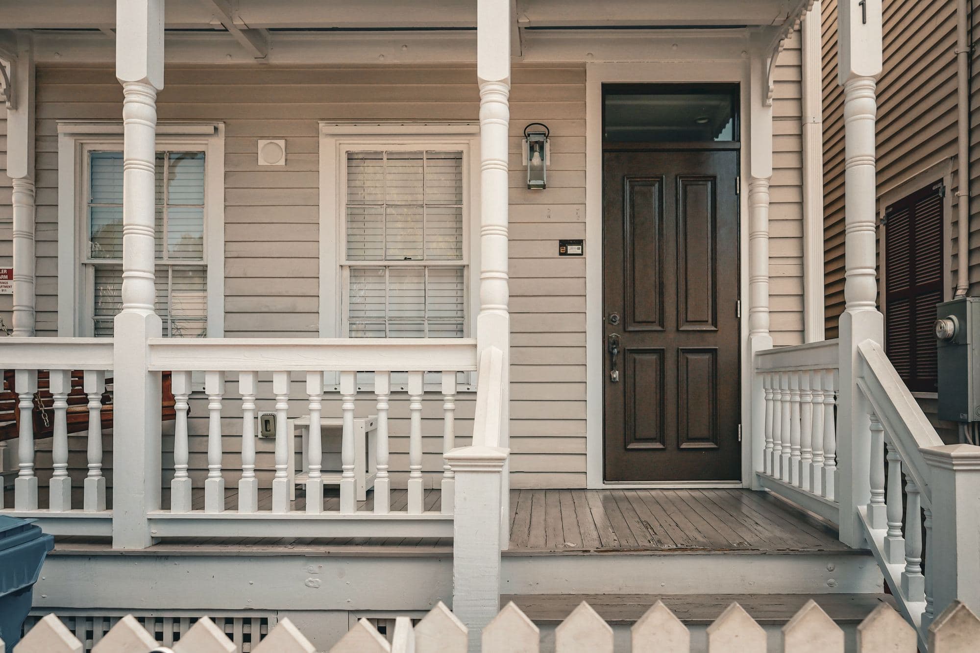Dark wood front door on a covered porch of a tan lap-sided house