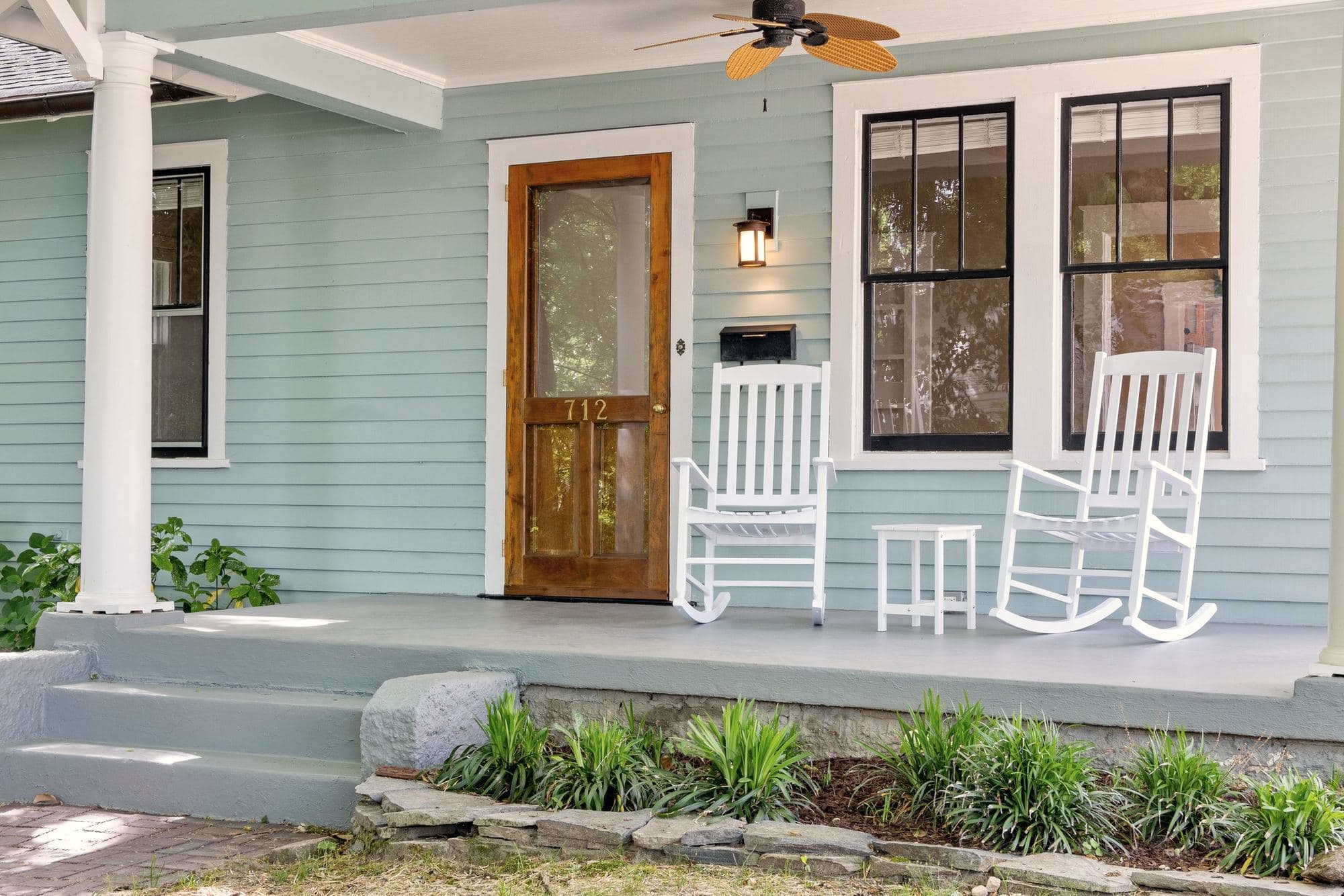 Wood and glass entry door on the front porch of a light blue craftsman home