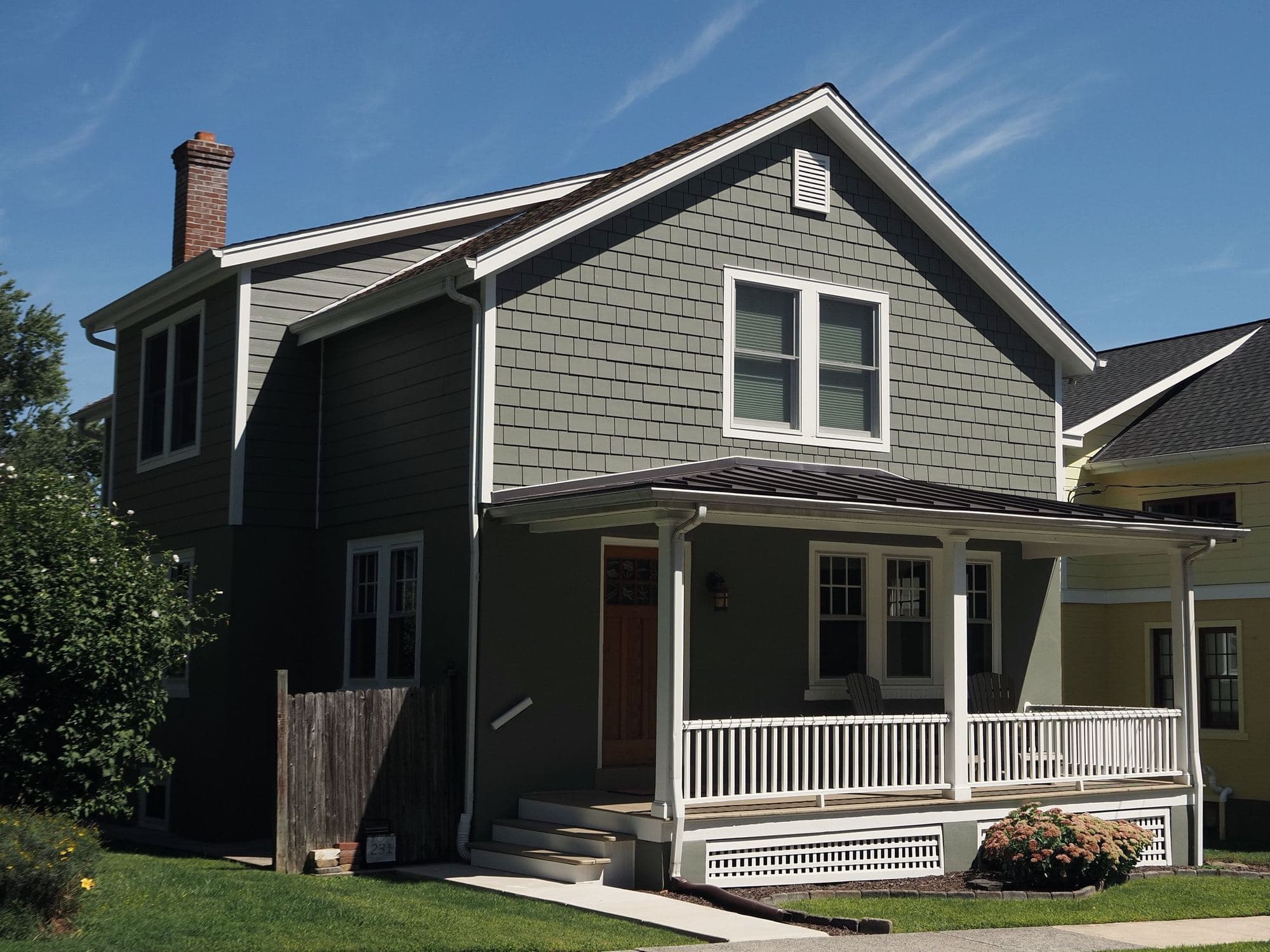 Green lap-sided home with freshly painted white trim and porch railings