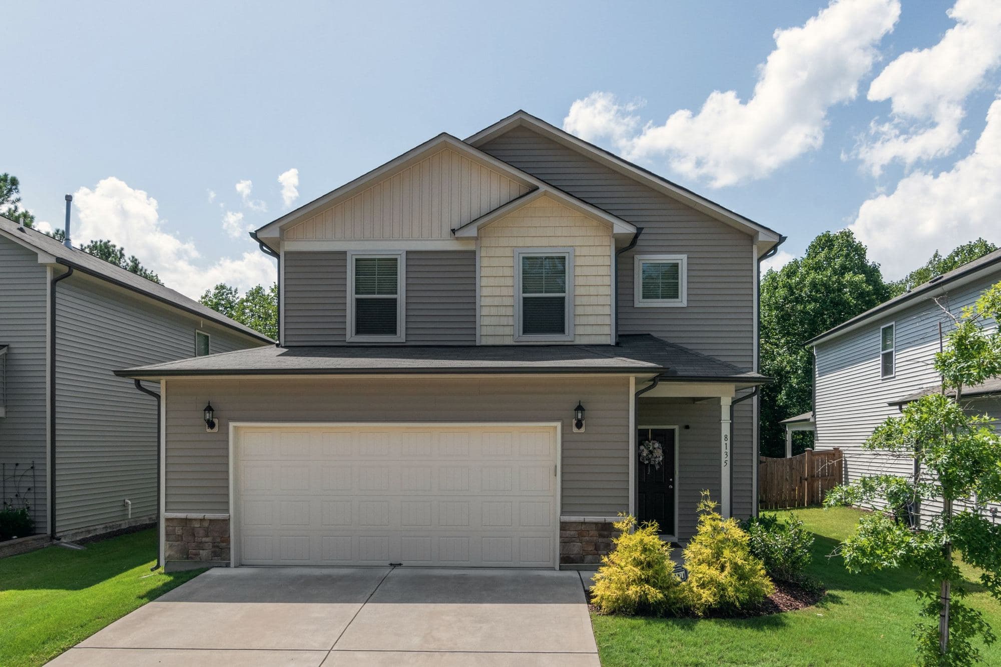 Front of a gray suburban home with white-trimmed windows above an attached garage